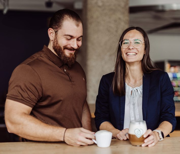 A man and a woman drink coffee and laugh